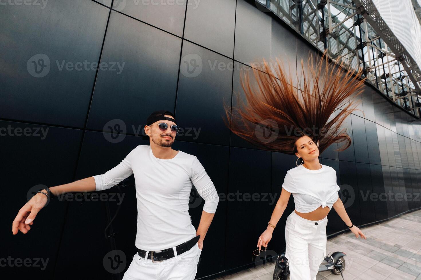 A girl and a guy are walking on electric scooters around the city, a couple in love on scooters. photo