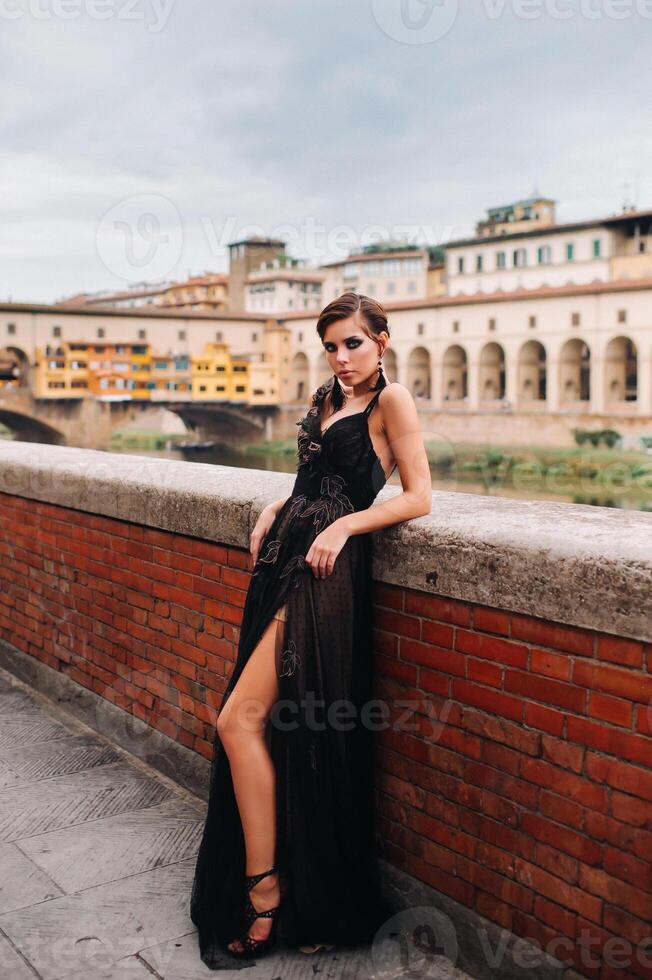 un hermosa elegante novia en un negro vestir camina mediante florencia, un modelo en un negro vestir en el antiguo ciudad de Italia foto