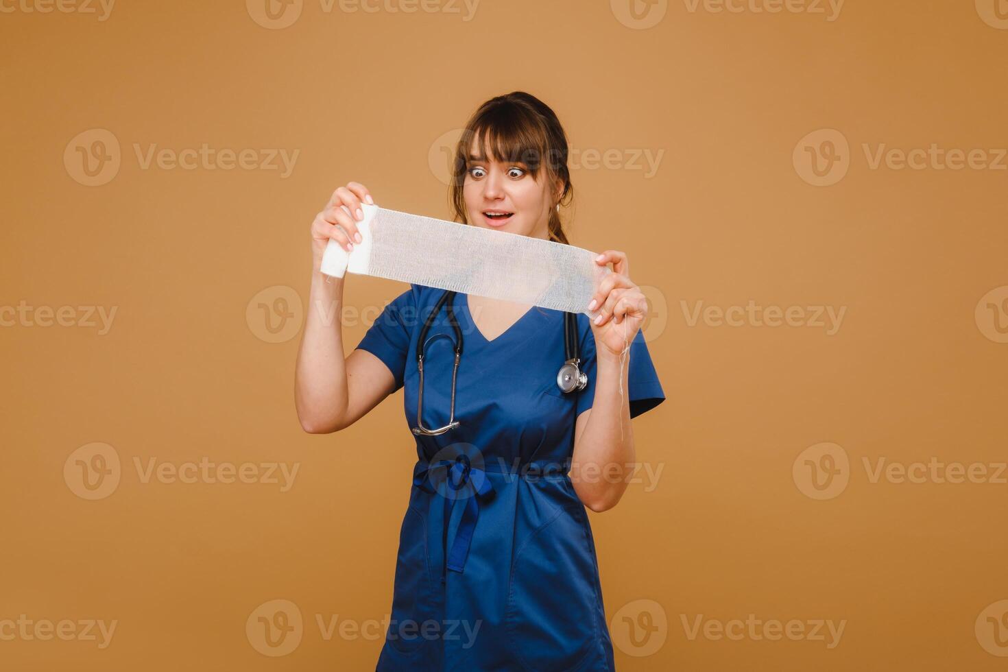 a female doctor in a white coat holds twisted gauze bandages for dressing wounds on a brown background photo