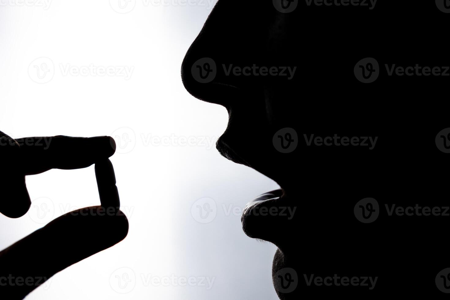 Taking pill. Silhouette of a woman taking a pill or drug. photo