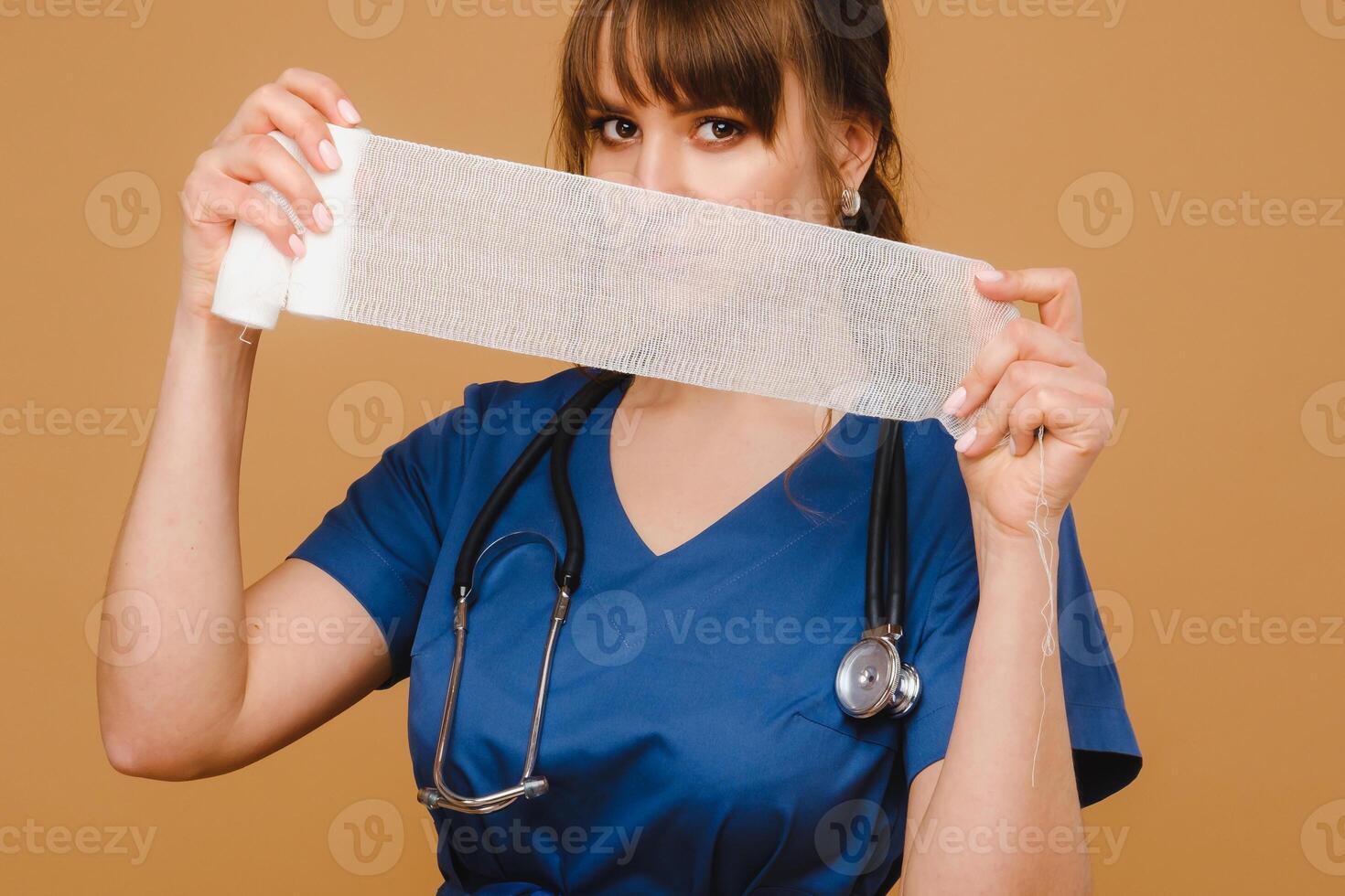 a female doctor in a white coat holds twisted gauze bandages for dressing wounds on a brown background photo