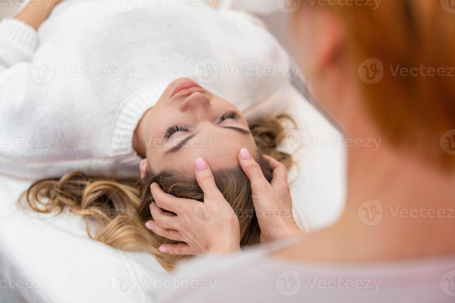 Healer performing by lightly touched access bars therapy on young woman head, stimulating positive change thoughts and emotions in salon. Alternative medicine concept photo