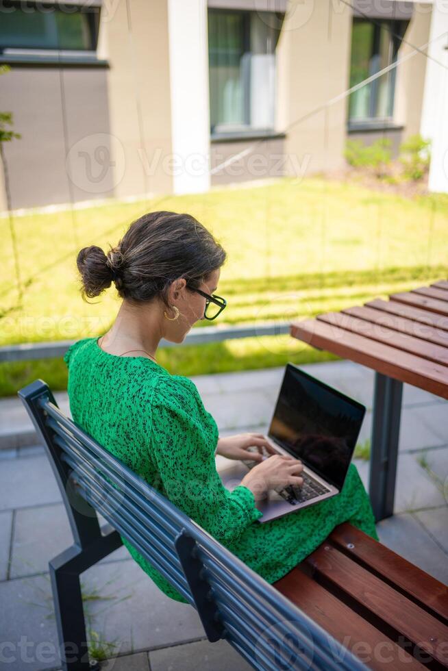 Caucasian woman working with laptop computer outside office. photo