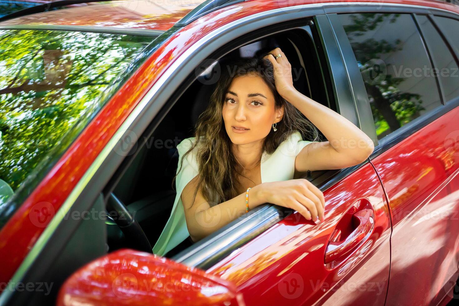 contento sonriente mujer conductor detrás el rueda rojo coche. ver mediante coche ventana foto