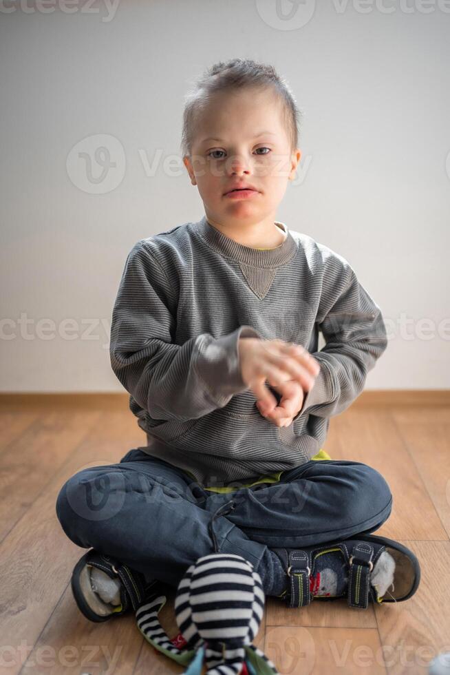 retrato de pequeño chico con abajo síndrome jugando con juguete en hogar dormitorio. alto calidad foto