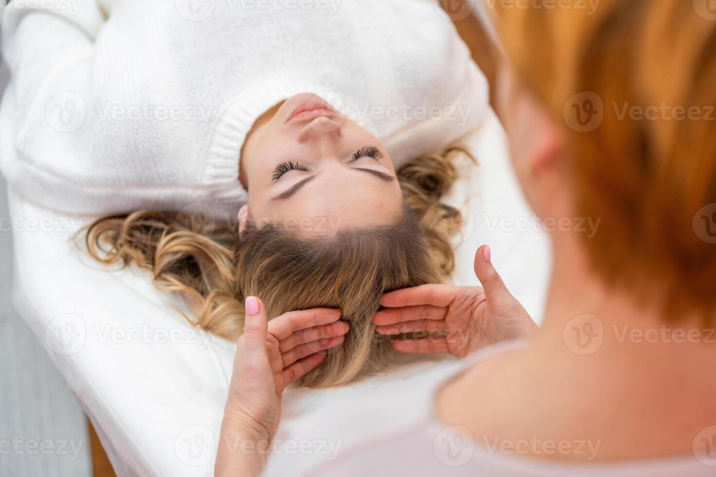 Healer woman performing by lightly touched access bars therapy on young woman head, stimulating positive change thoughts and emotions. Alternative medicine concept photo