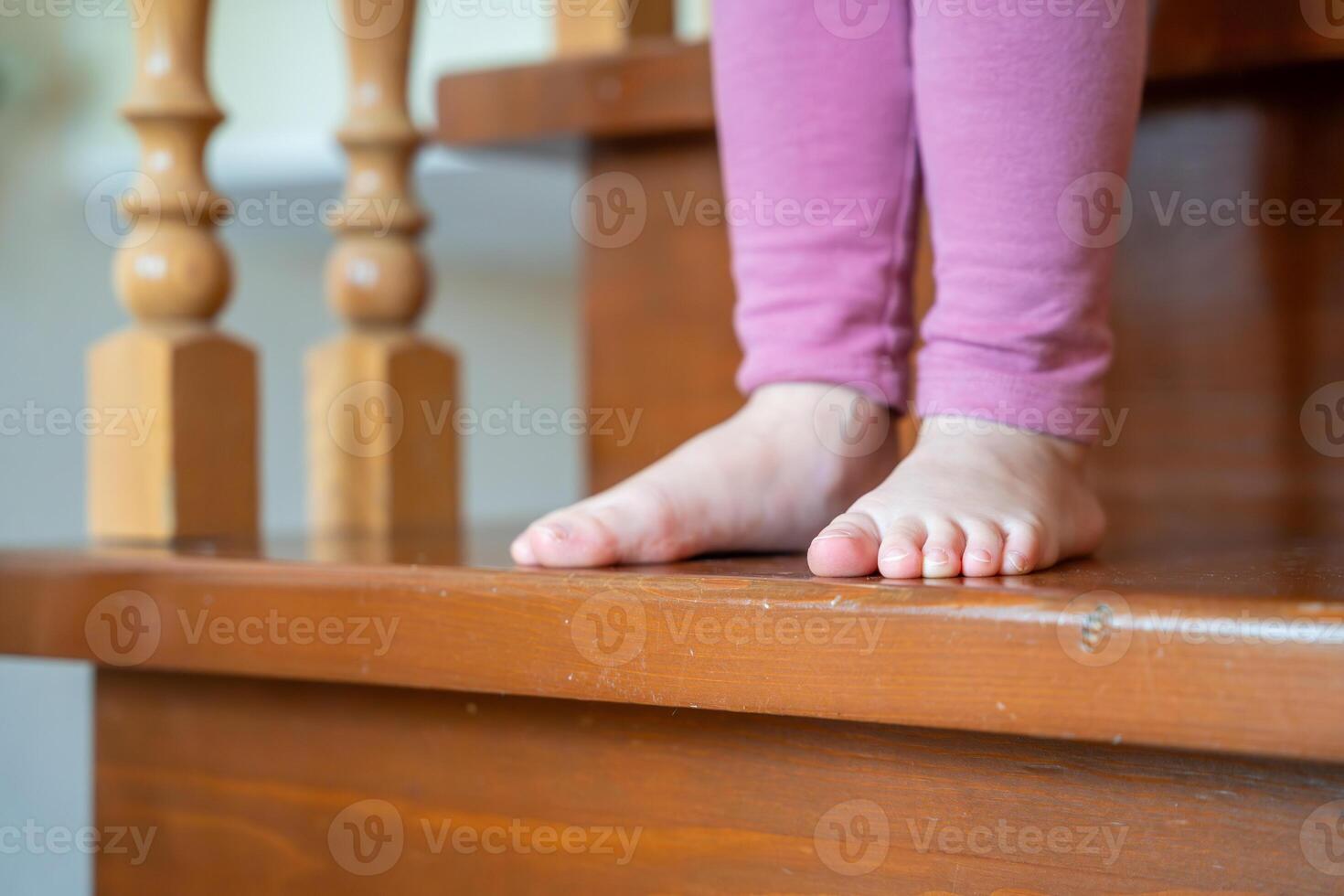 de cerca de pequeño niña pies yendo abajo el escalera a hogar foto