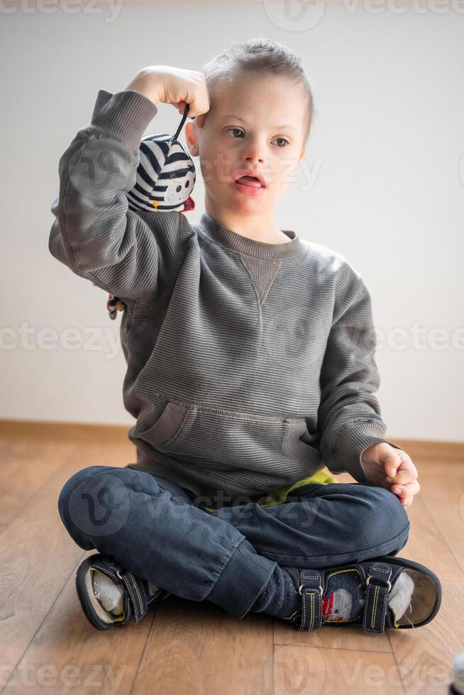 retrato de pequeño chico con abajo síndrome jugando con juguete en hogar dormitorio. alto calidad foto