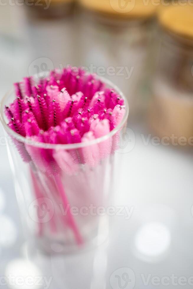 Pink eyelash brushes for eyelash extension in glass cup photo