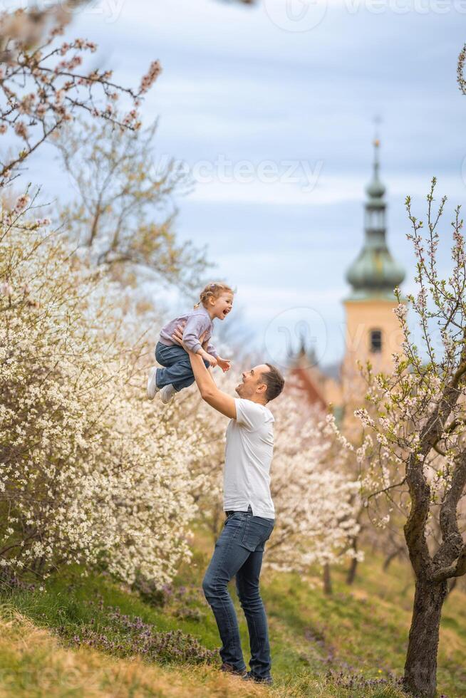 padre y hija teniendo un divertido juntos debajo un floreciente árbol en primavera parque petrin en praga, Europa foto