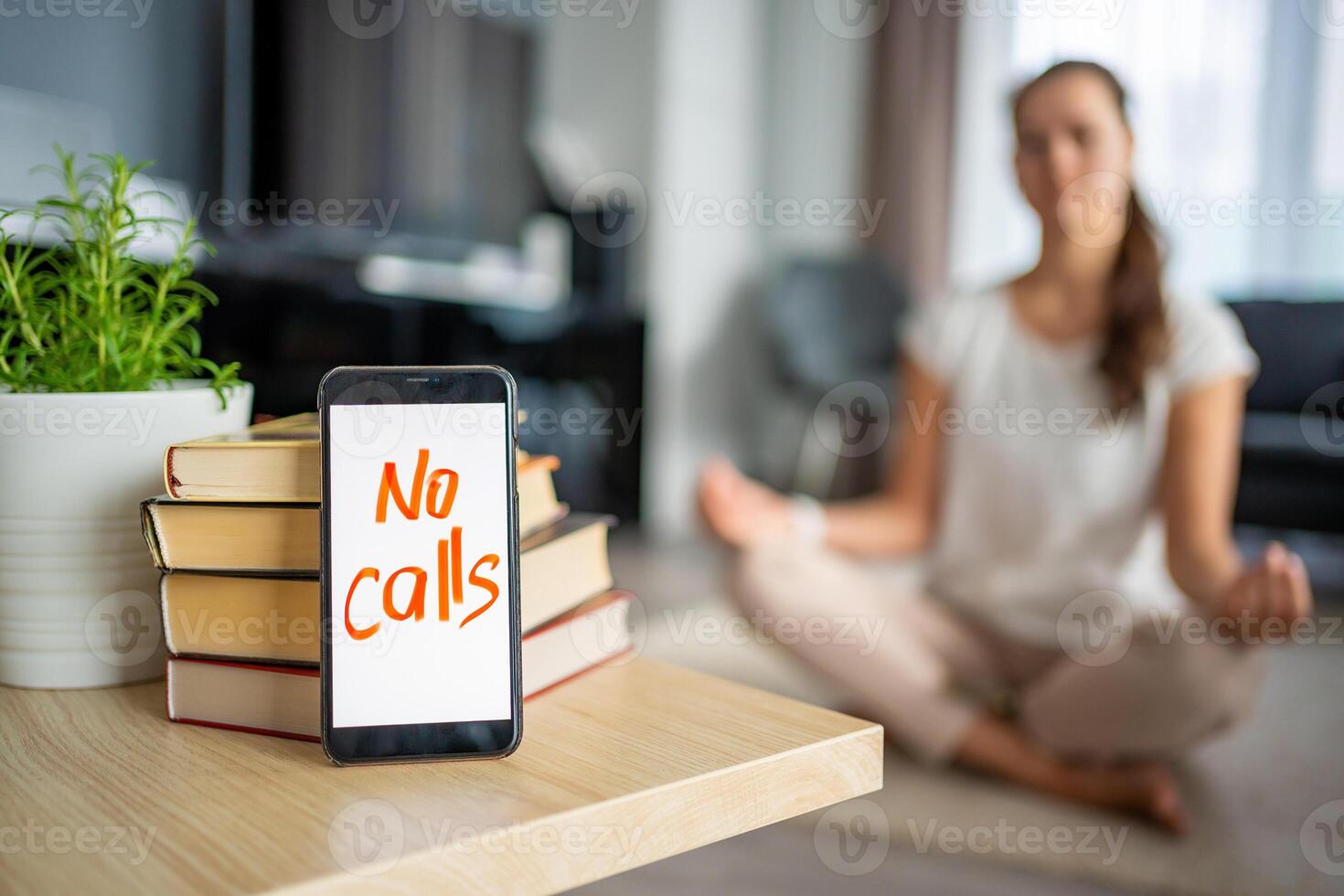 Digital detox concept. In the foreground is a smartphone with the text No Calls and woman meditating in the background photo