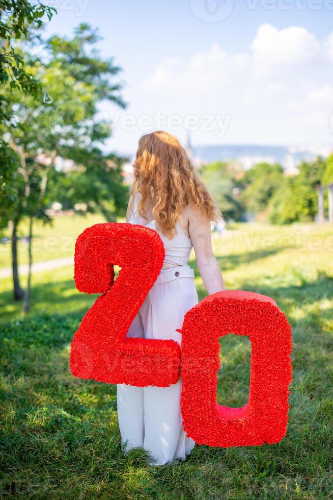 Beautiful woman with paper number with flowers in hand - decorations made with your own hands. Small business concept. photo