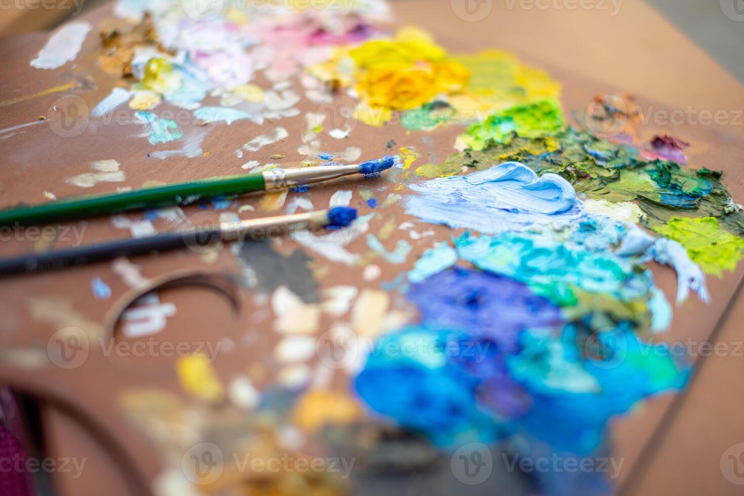 Palette with multi-colored paints and brushes, woman painting picture photo