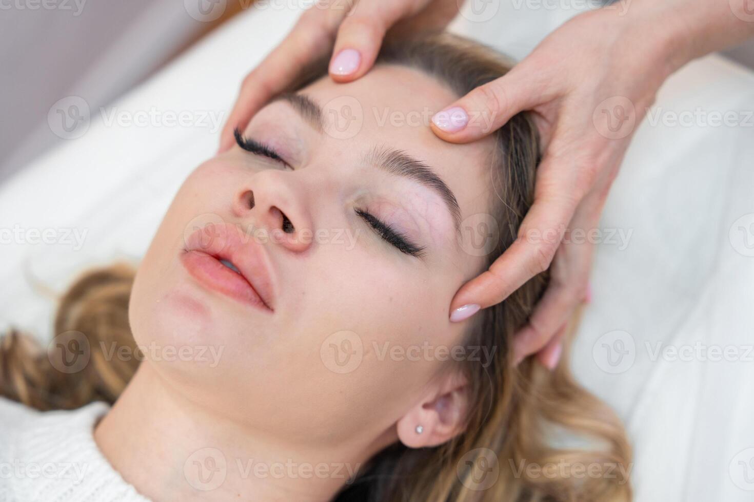 Close up view of healer hands performing by lightly touched access bars therapy on young woman head, stimulating positive change thoughts and emotions. Alternative medicine concept photo