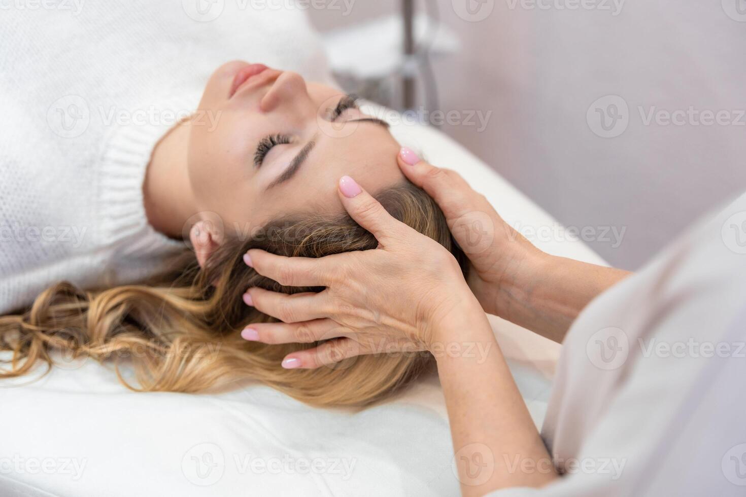 Healer performing by lightly touched access bars therapy on young woman head, stimulating positive change thoughts and emotions. Alternative medicine concept photo