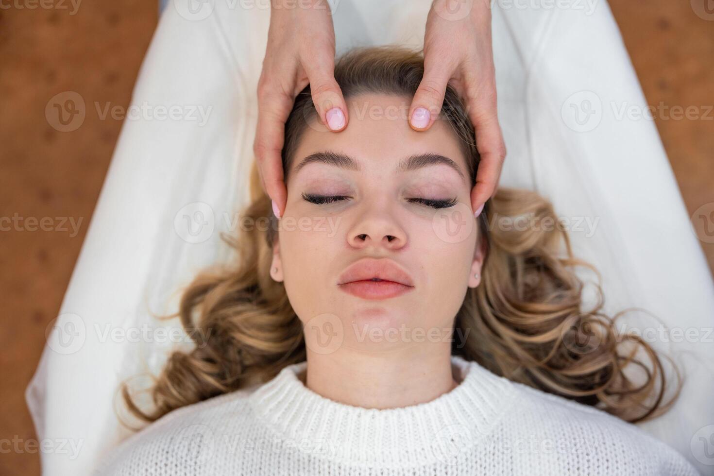 Top view of healer hands performing by lightly touched access bars therapy on young woman head, stimulating positive change thoughts and emotions. Alternative medicine concept photo