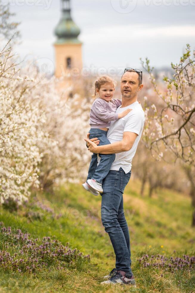 padre y hija teniendo un divertido juntos debajo un floreciente árbol en primavera parque petrin en praga, Europa foto