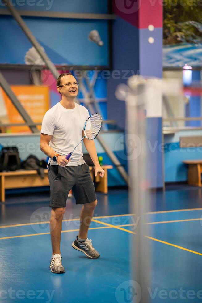 Man playing badminton in sport wear on indoor court photo