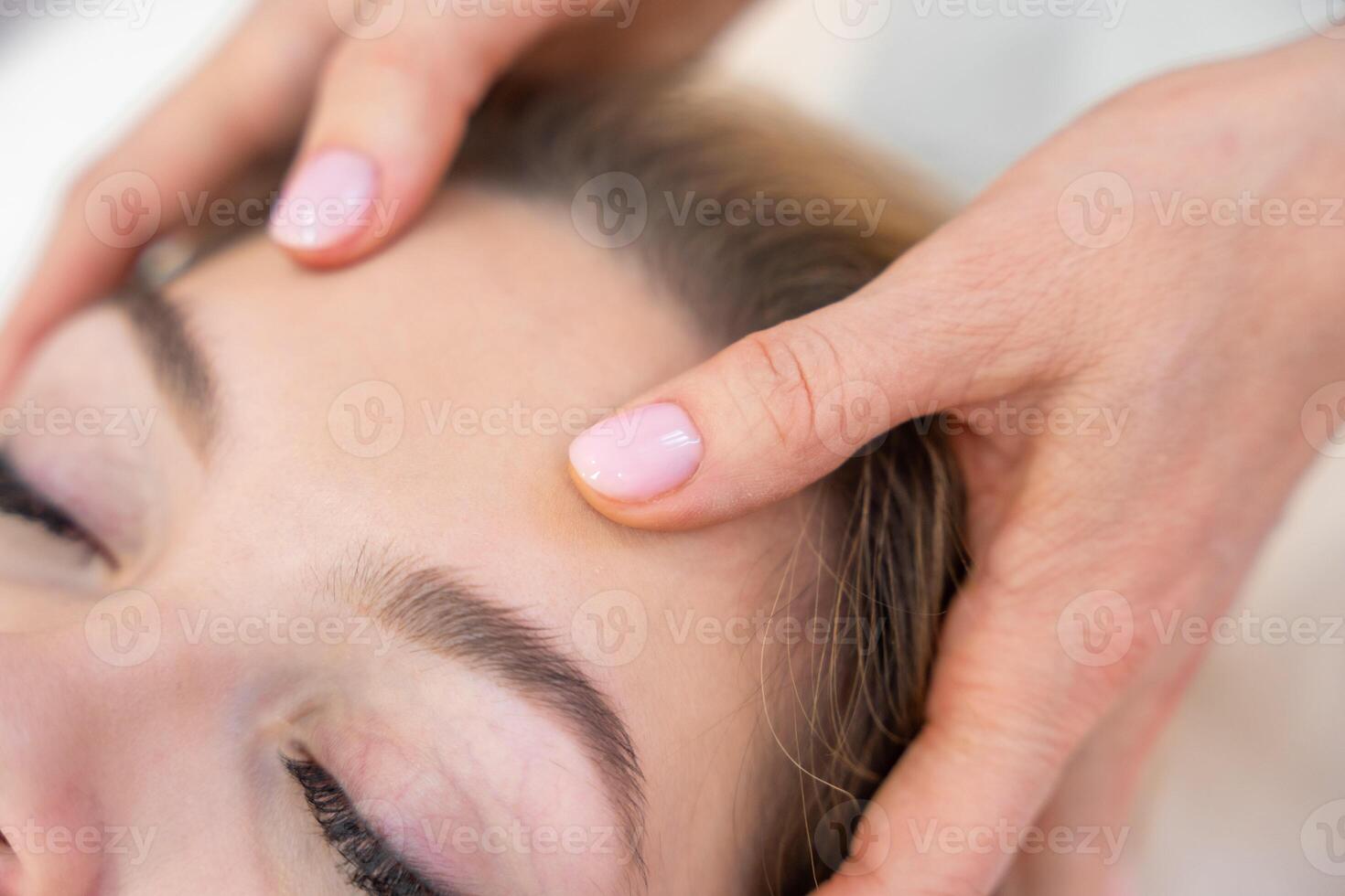 Close up view of healer hands performing by lightly touched access bars therapy on young woman head, stimulating positive change thoughts and emotions in salon. Alternative medicine concept photo