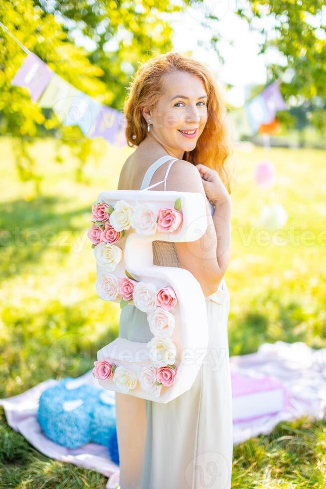 Beautiful woman with paper number with flowers in hand - decorations made with your own hands. Small business concept. photo