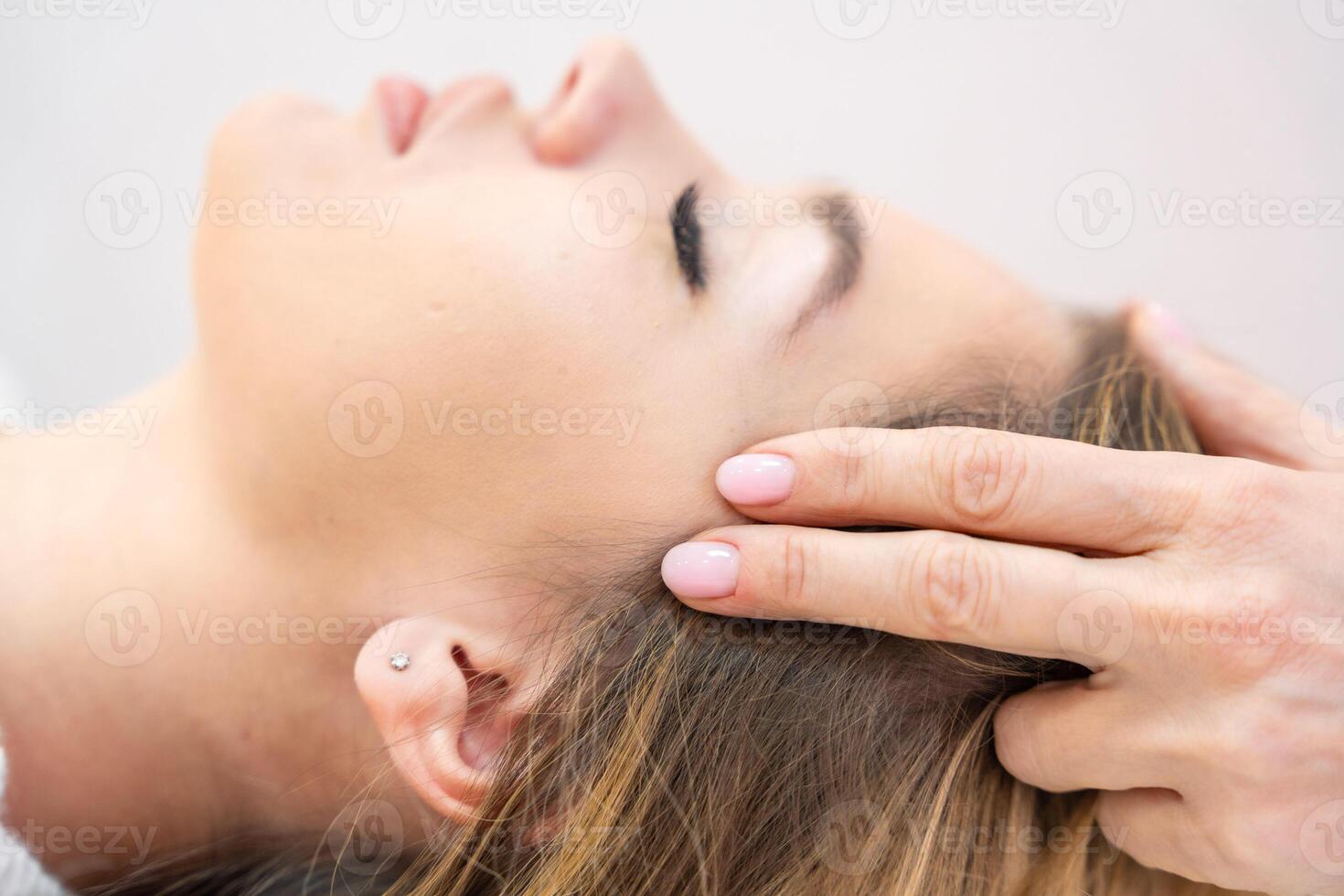 Close up view of healer hands performing by lightly touched set of 32 points of access bars on young woman head, stimulating positive change thoughts and emotions. Alternative medicine concept photo