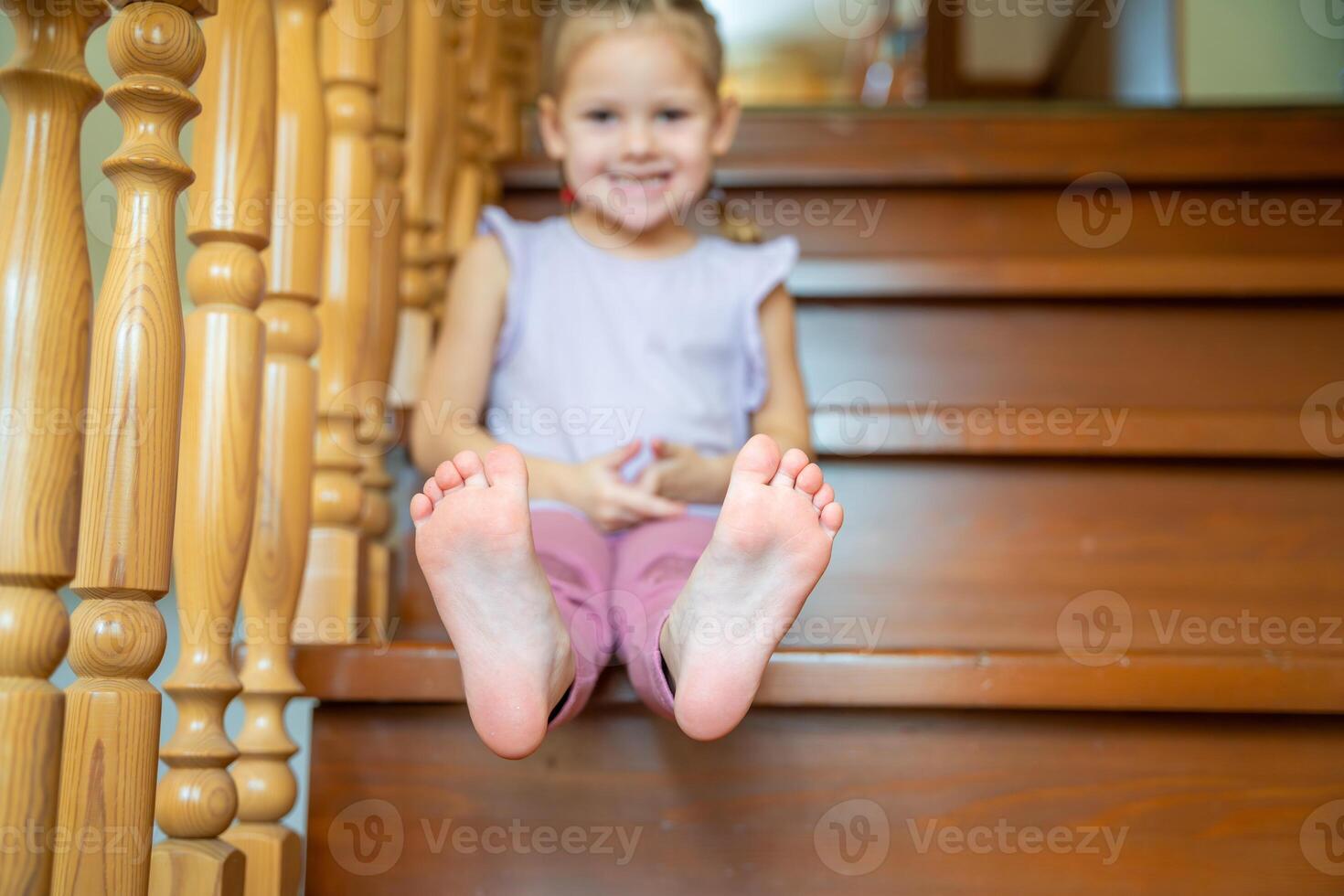 Closeup of infant toddler feet, child sitting on stairs at home. Focus on feet photo