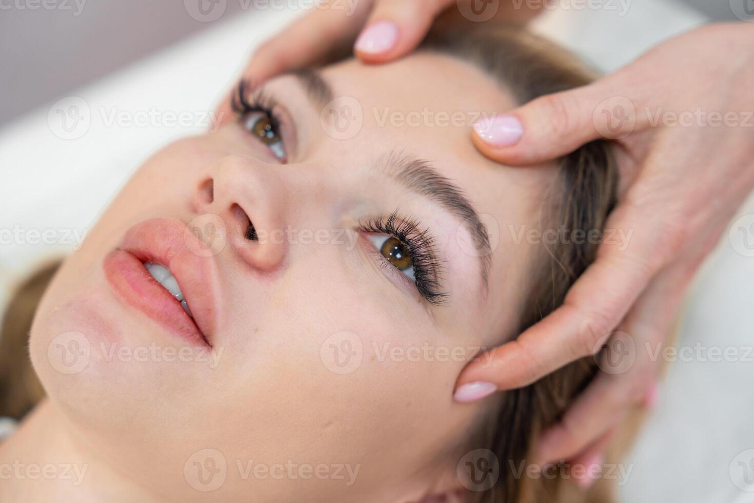 Healer performing set of 32 points of access bars on young woman head, stimulating positive change thoughts and emotions. Alternative medicine concept photo