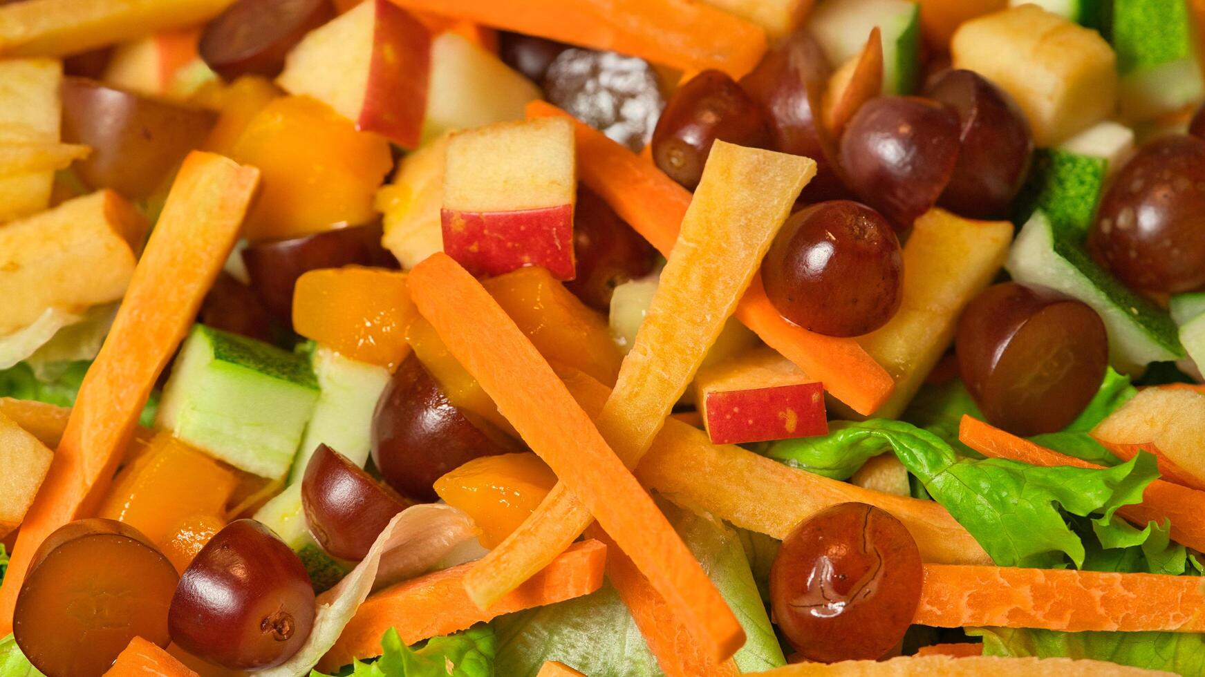 a salad with carrots, apples, and grapes photo