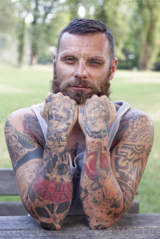 portrait of bearded man with elbows on the table in the park photo