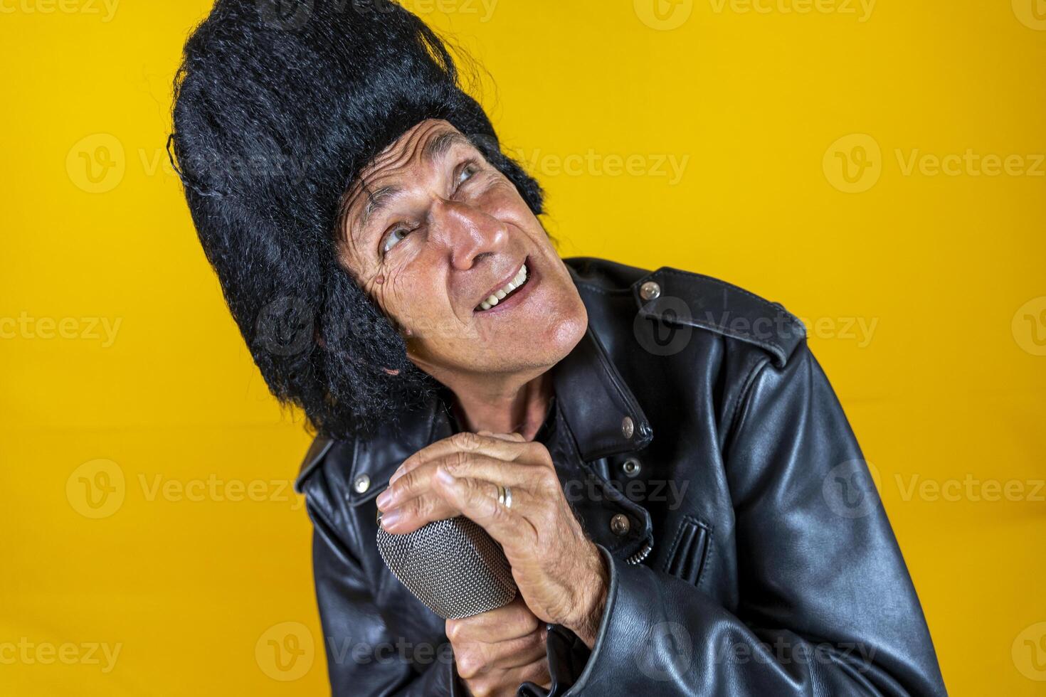 Funny portrait of mature rocker. An old singer dressed in rockabilly style in action photo