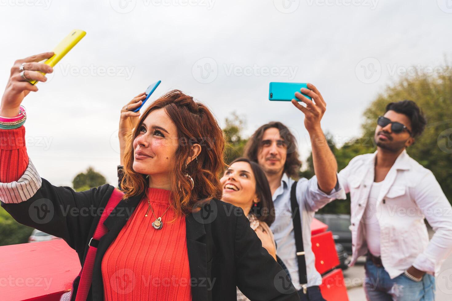 group of multi-cultural best friends take a selfie with smart phones outdoors photo