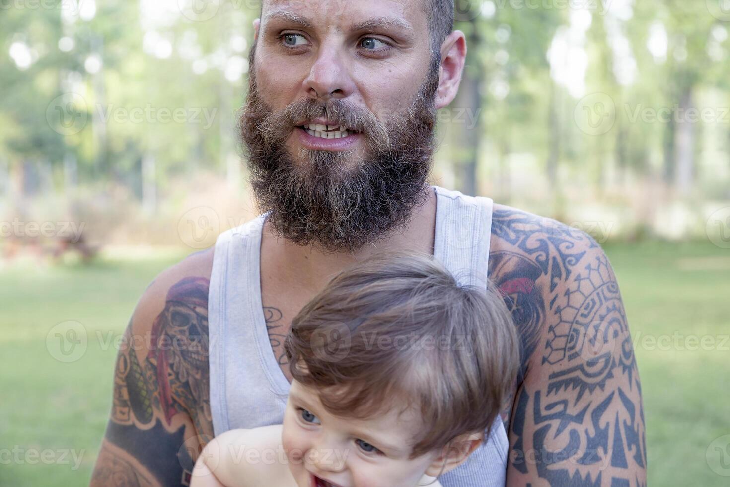 tattooed father have fun with his son in the park photo