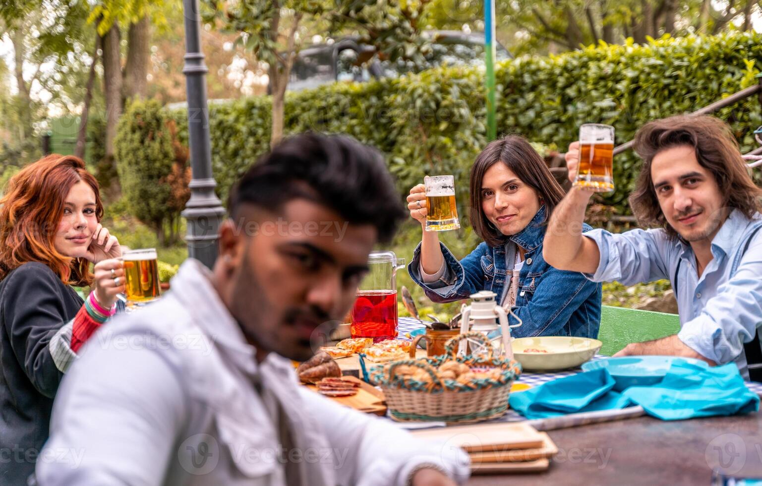 grupo de multicultural amigos teniendo divertido a jardín fiesta - joven personas sonriente juntos comiendo comida y Bebiendo cerveza foto