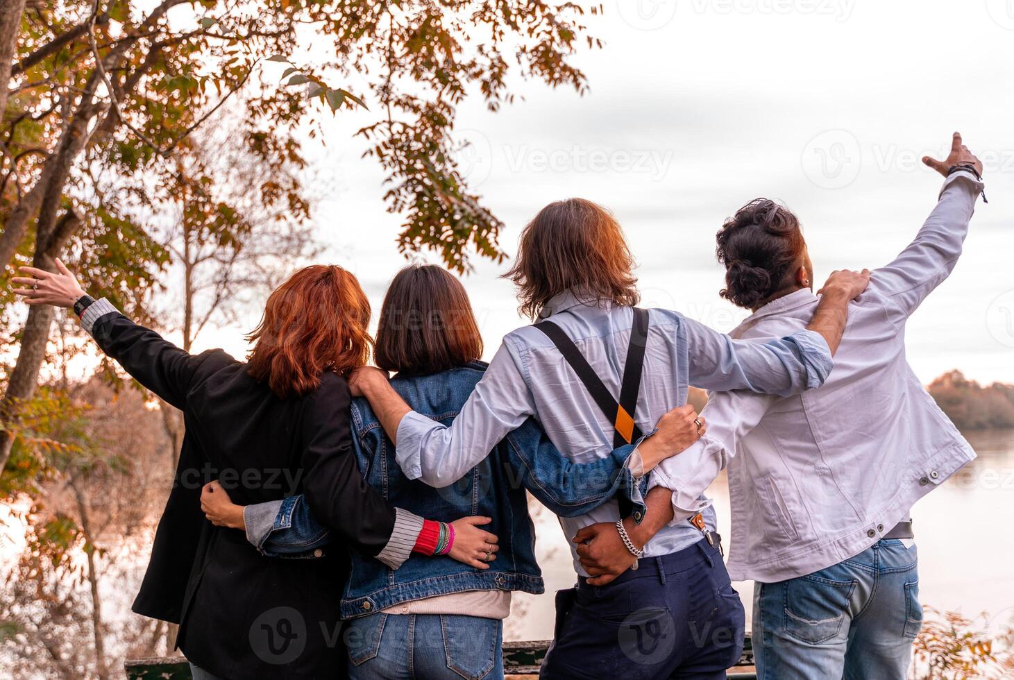 grupo de mejor amigo tener divertido en frente de un grande río en otoño a puesta de sol foto