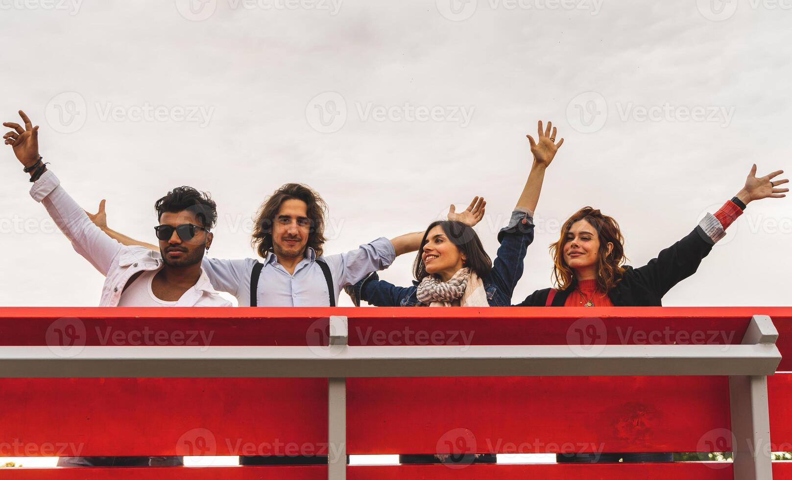 group of best friends screaming to the sky from a big red bench photo