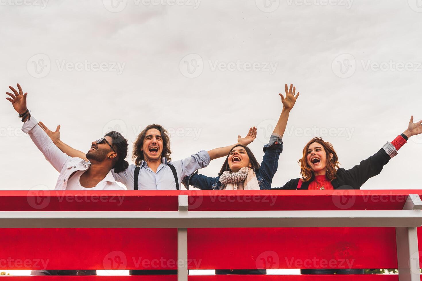 group of best friends screaming to the sky from a big red bench photo