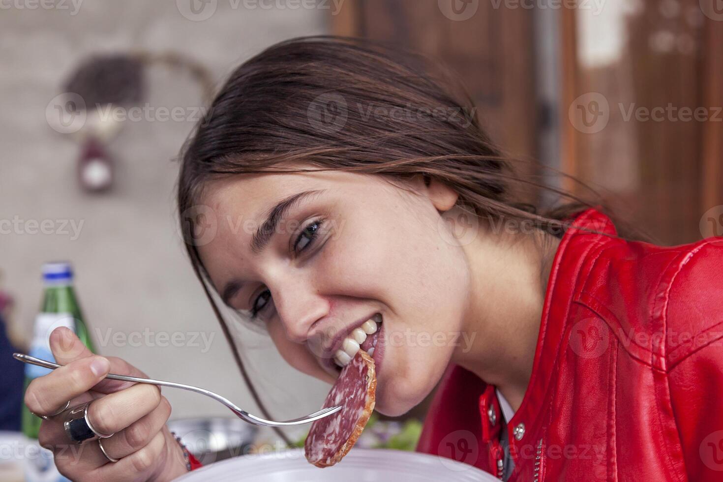 retrato de linda niña mientras comiendo un rebanada de italiano salami foto