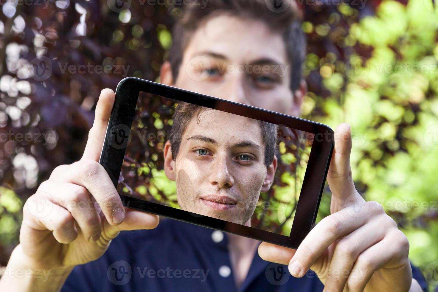 young millennial man taking a selfie with smart phone outdoors photo