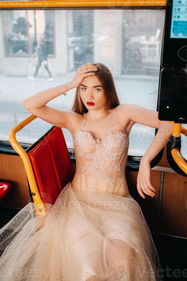 un novia en un Boda vestir con largo pelo paseos en el transporte de el ciudad de Breslavia. modelo novia sentado en un autobús asiento, Polonia foto