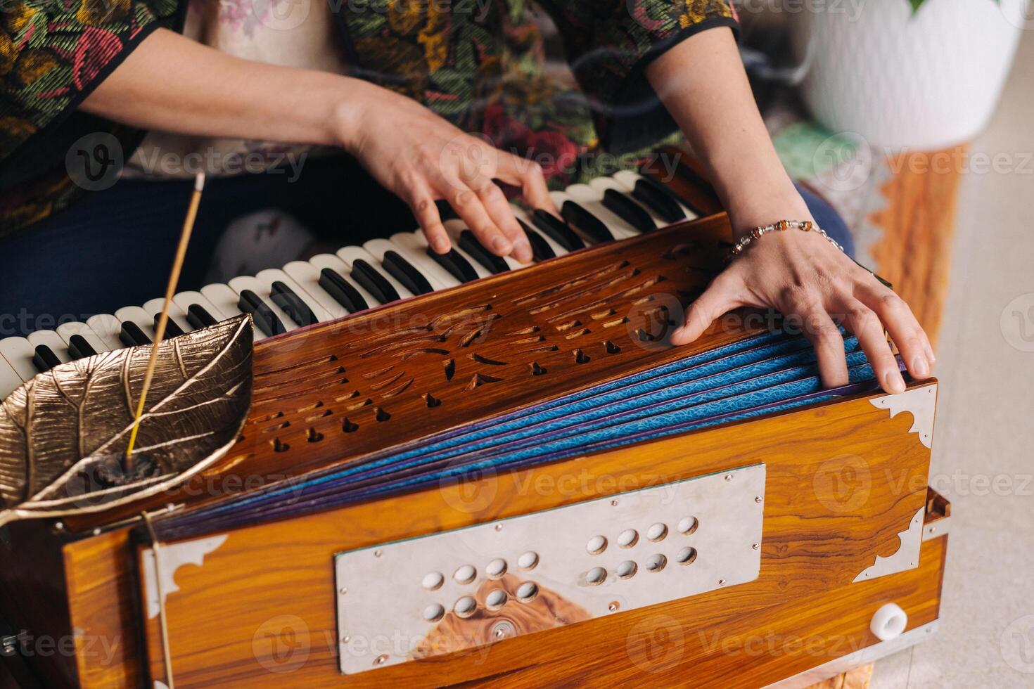 Hands of a woman sitting on the floor and playing the harmonium during the practice of kundalini yoga photo