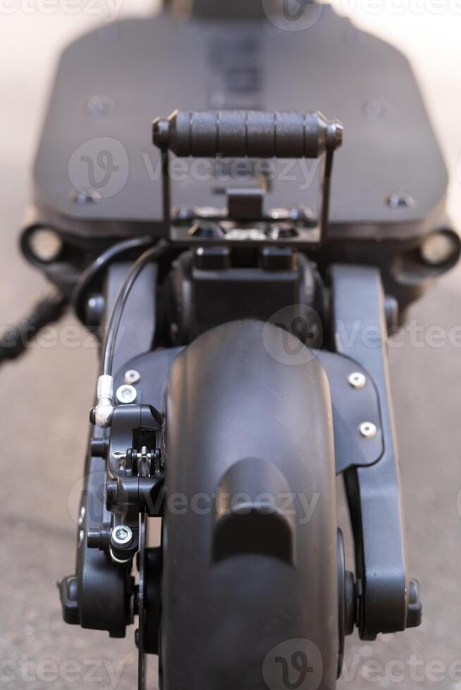 The back of the electric scooter with a foot rest on the asphalt background in sunny weather photo