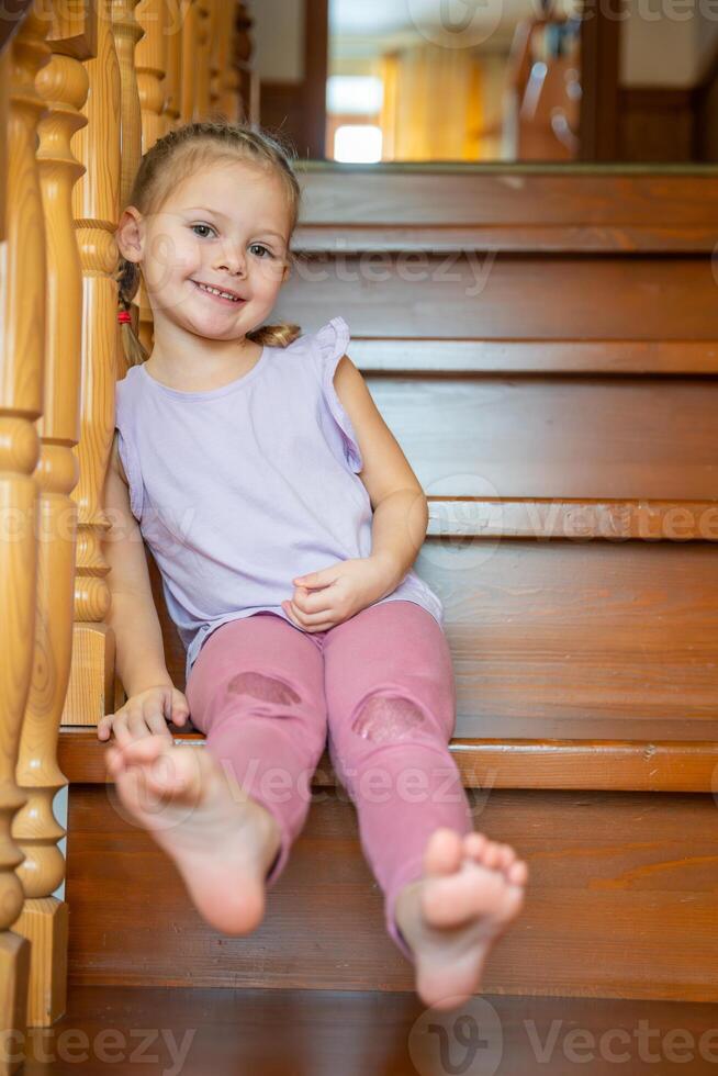 Cute Little girl is playing on stairs at home. Dangerous situation at home. Child safety concept. photo