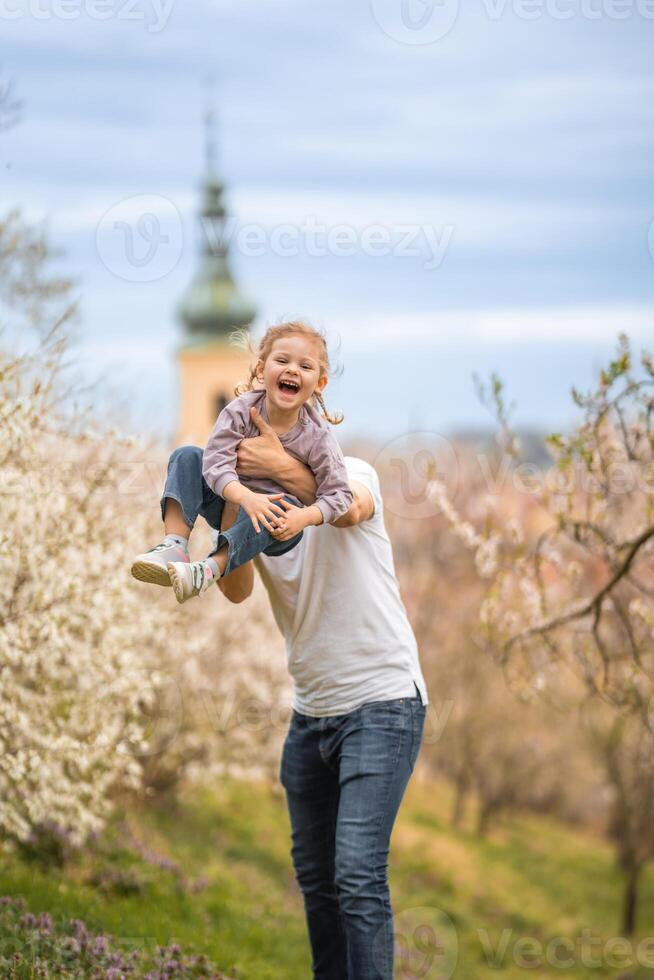 Father and daughter having a fun together under a blooming tree in spring park Petrin in Prague, Europe photo