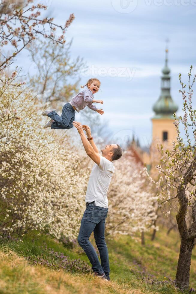 Father and daughter having a fun together under a blooming tree in spring park Petrin in Prague, Europe photo