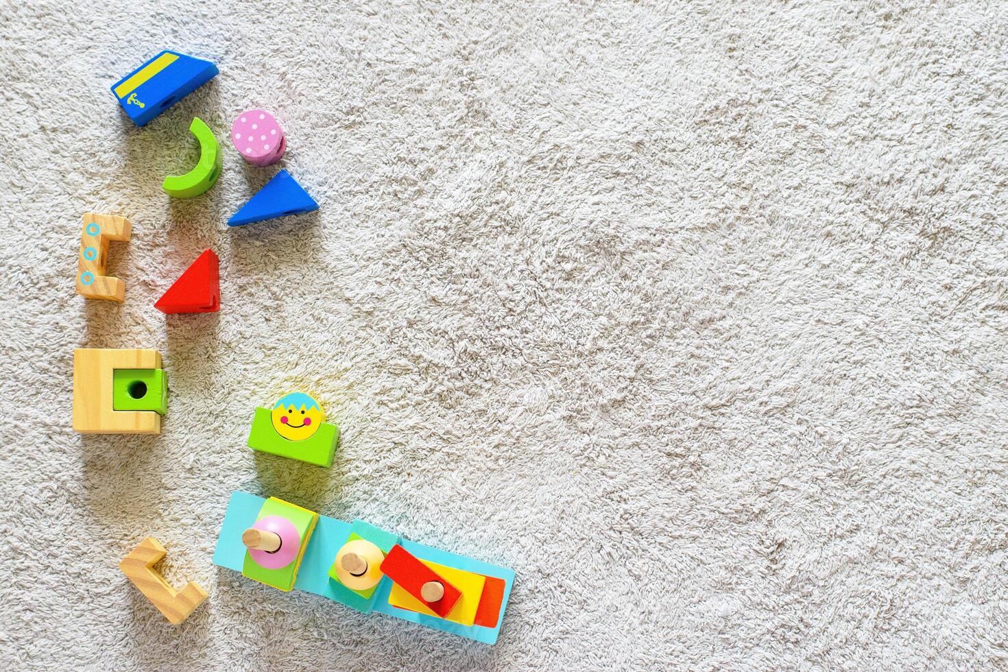 Colorful wooden pyramid with geometric details on a white cotton carpet. Eco friendly, plastic free toys for toddler. Space for text photo