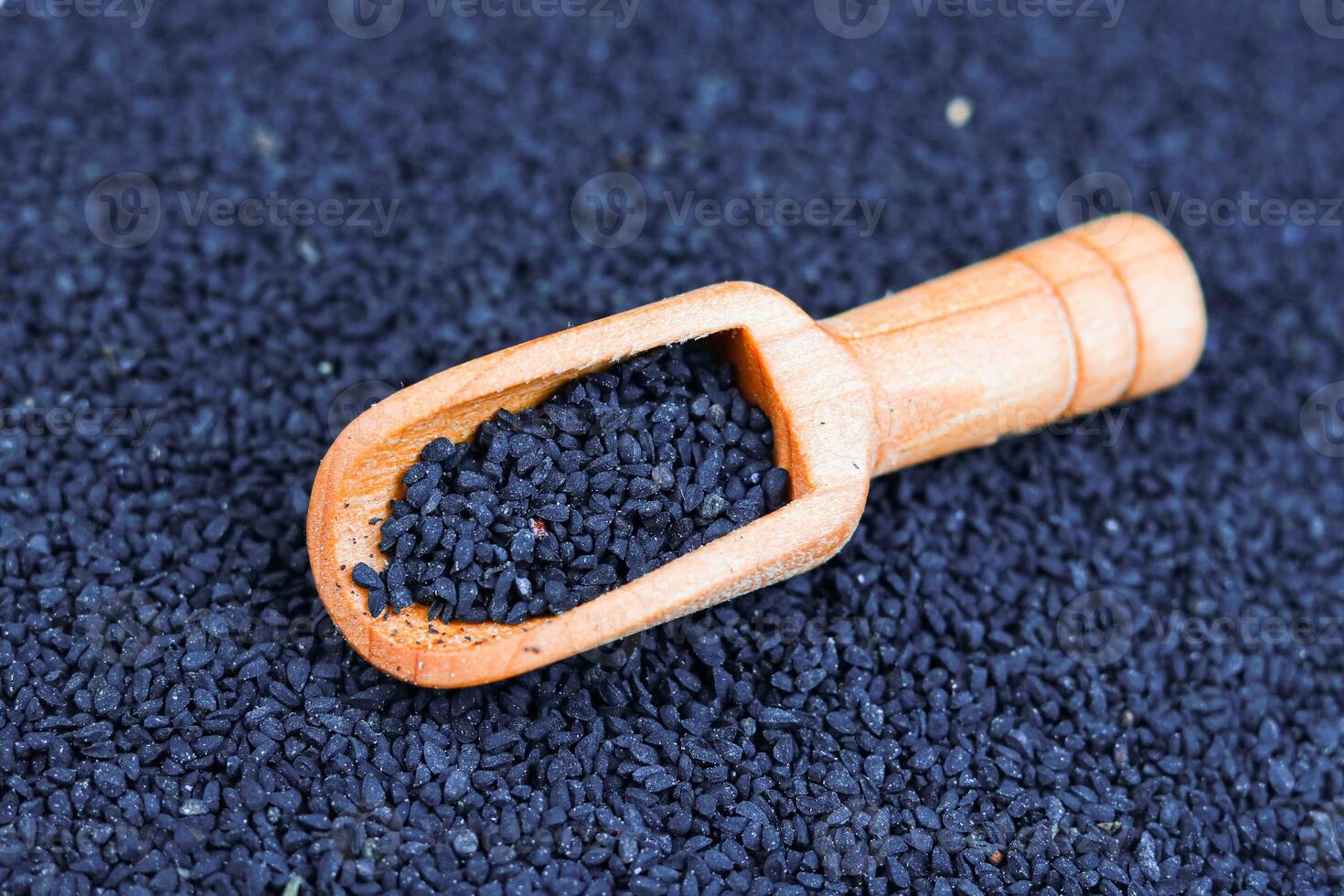 Black Cumin seeds in wooden spoon on Black Cumin background. photo
