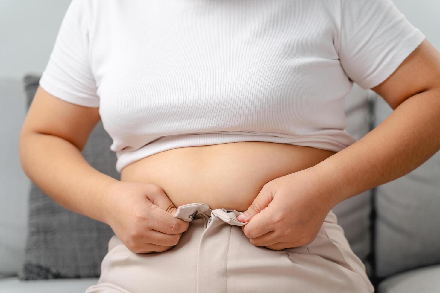 Fat chubby woman with big belly trying to wear tight pants. photo