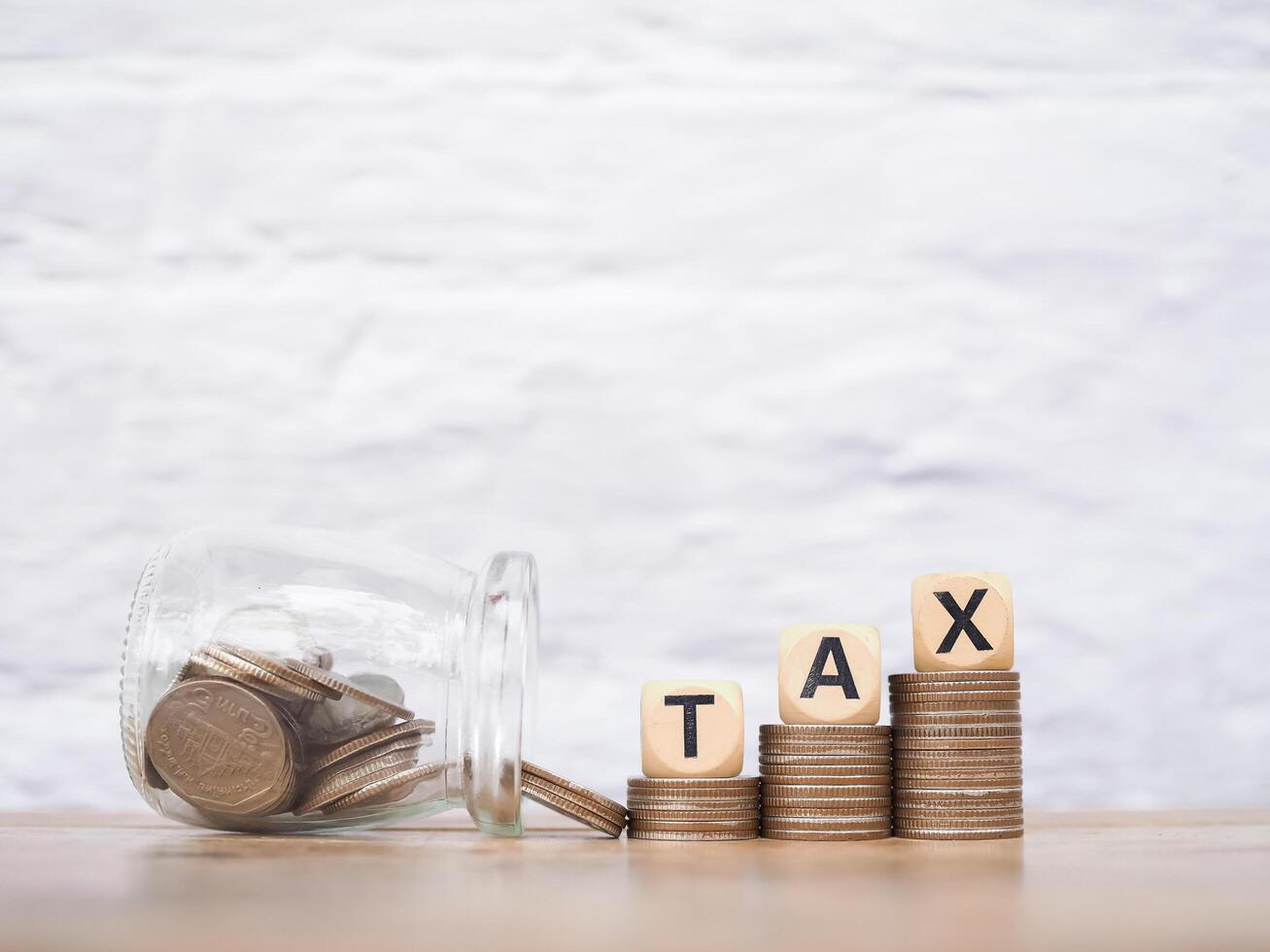 Wooden words with the TAX on stack of coins. The concept about saving money and manage time to paying tax photo