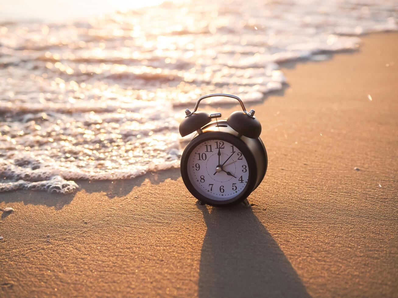 Black alarm clock on the beach in the sunset time. The concept about Time to summer, Travel, Vacation and Relaxation photo