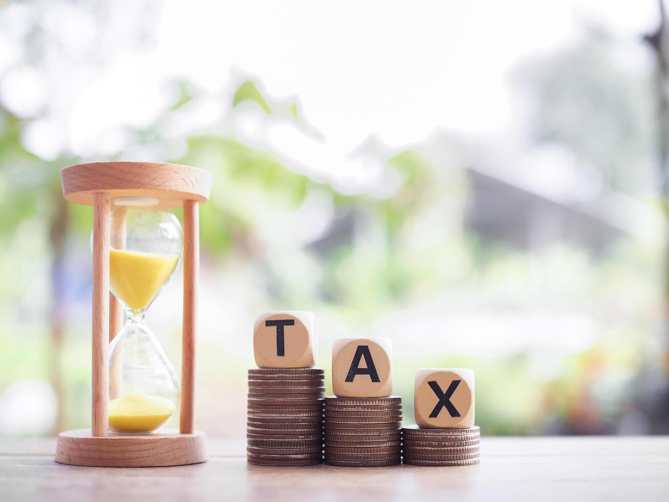 Hourglass, Wooden blocks with the word TAX on stack of coins. The concept about saving money and manage time to paying tax photo